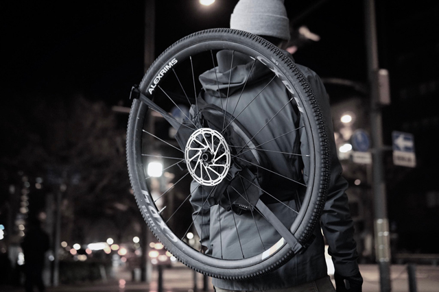 ハイノウのダックパックで自転車のホイールを背負う男